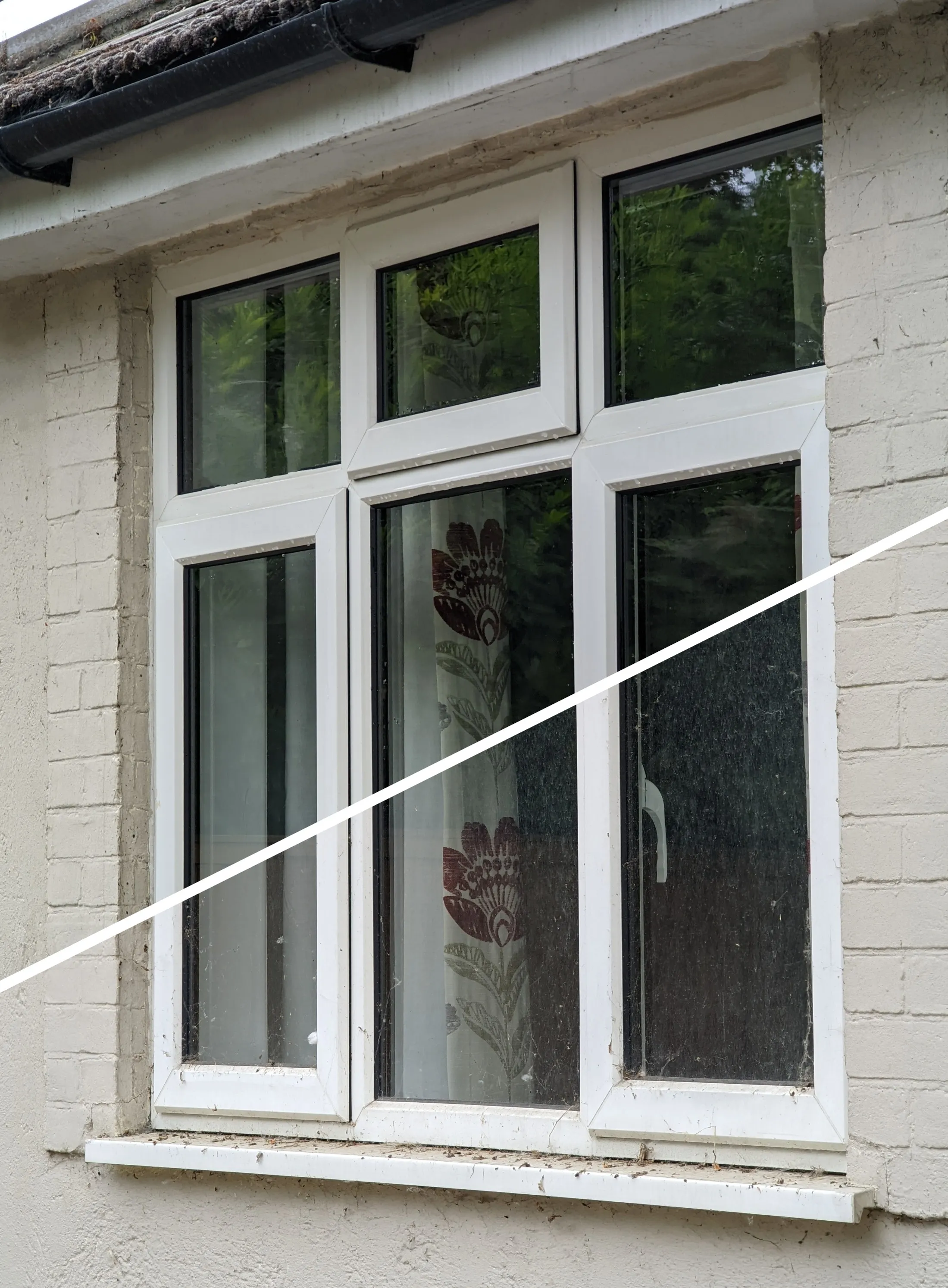 The same window part-way through cleaning. Above the white line the glass and frames are clean; below it they are still dusty and covered in cobwebs.